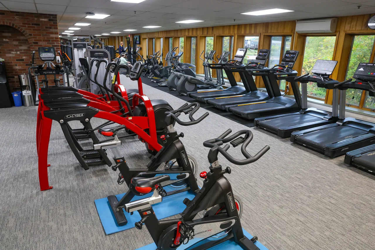 Spin bikes and red Cybex machines in front of the treadmill row at RecFit