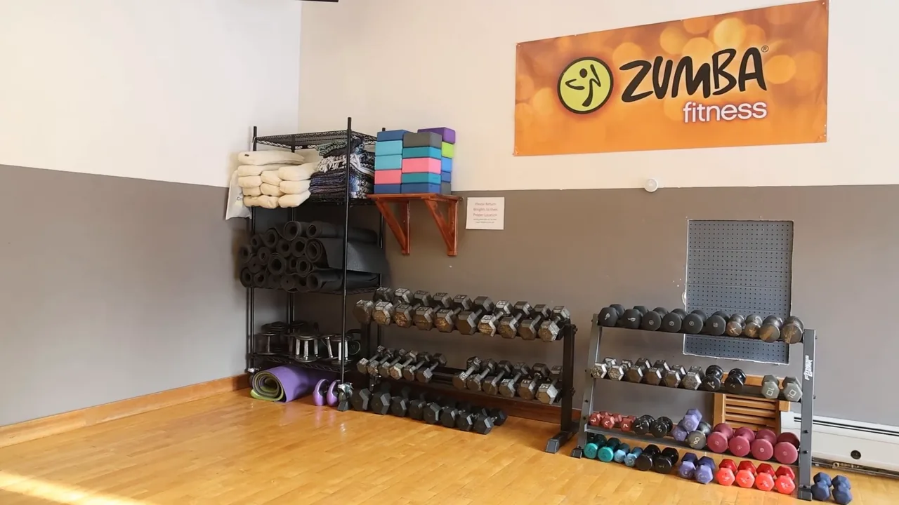 RecFit's group fitness studio: a wood floor, racks of dumbbells and mats