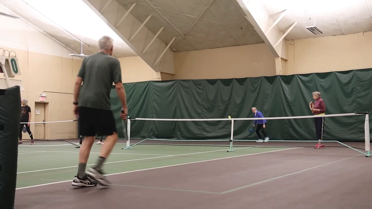Pickleball doubles on RecFit's court, seen from behind one player