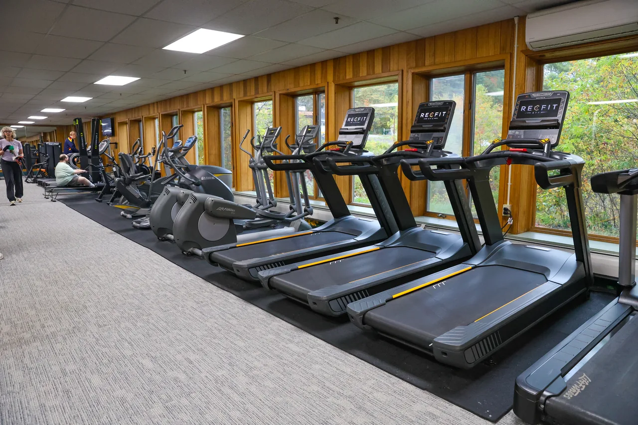 Treadmills and ellipticals on RecFit's cardio floor, members at the far end